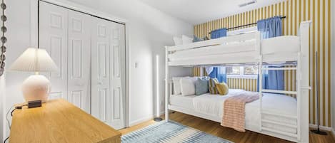 A room with a bunk bed, a desk with a lamp, and a door.