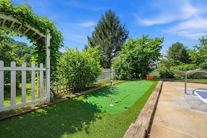 A well-maintained backyard with a putting green, a white picket fence, and a swimming pool. - Sleeps 20 Sport Court Game Room Sauna Spa (Asheville)