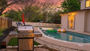 Ein Garten mit Grill, Schwimmbecken und einem Haus.
