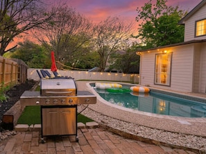 Ein Garten mit Grill, Schwimmbecken und einem Haus.