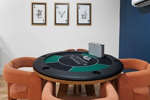 Ein Zimmer mit Pokertisch, gerahmten Spielkarten an der Wand und einem Heizkörper.