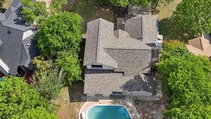 Ein Wohnhaus mit Swimmingpool, umgeben von Bäumen und einem gepflegten Rasen.