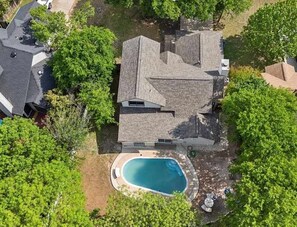Ein Wohnhaus mit Swimmingpool, umgeben von Bäumen und einem gepflegten Rasen.