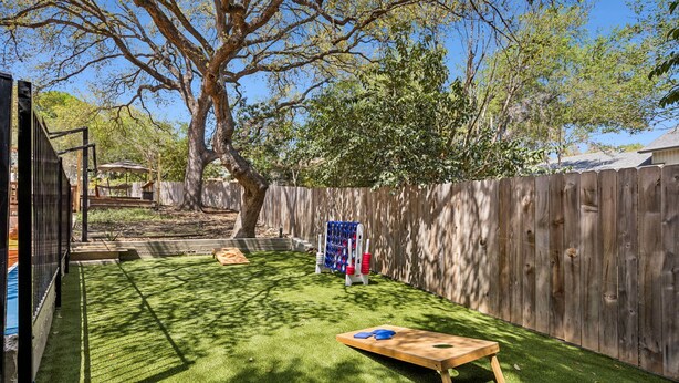 A backyard with artificial grass, a wooden play table, and a wooden fence. - The Haven on Twisted Wood 4BR 3BA Sleeps 12 (San Antonio)