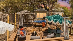 Eine Holzterrasse mit Gartenmöbeln, darunter eine Sitzecke, Stühle und ein Tisch.