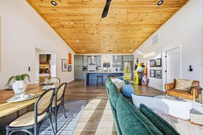 A modern kitchen with a central island, wooden ceiling, and a dining area with a table and chairs. - Bryson City Cabin Sauna Hot Tub (Bryson City)