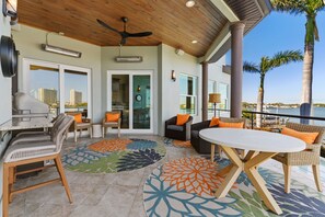 An outdoor patio with a grill, wicker furniture, and a view of the ocean. - Luxury Waterfront 4Br Private Heated Pool Hot Tub (St. Petersburg)