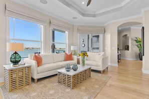 A spacious living room with a large window, a sofa, a coffee table, and a view of the sea. - Luxury Waterfront 4Br Private Heated Pool Hot Tub (St. Petersburg)