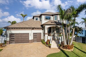 A two-story house with a garage, a covered porch, and a view of the sea. - Luxury Waterfront 4Br Private Heated Pool Hot Tub (St. Petersburg)