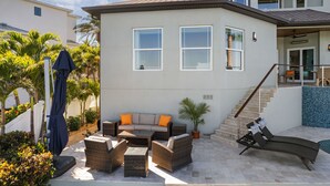 Una casa moderna de dos pisos con un patio que cuenta con mobiliario exterior y una piscina.