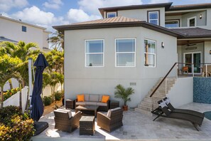 A modern two-story house with a patio area featuring outdoor furniture and a pool. - Luxury Waterfront 4Br Private Heated Pool Hot Tub (St. Petersburg)
