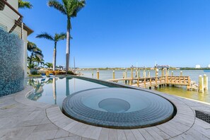 A swimming pool with a circular hot tub, palm trees, and a dock extending into the water. - Luxury Waterfront 4Br Private Heated Pool Hot Tub (St. Petersburg)