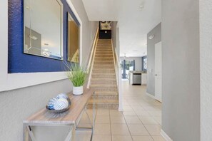 A hallway with a wooden staircase, a potted plant, and a small table with a decorative item. - Disney Min Away - Pool Patio Playground (Kissimmee)