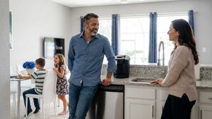 A modern kitchen with a dishwasher, a coffee maker, and a child playing with a book. - Disney Min Away - Pool Patio Playground (Kissimmee)