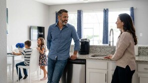 A modern kitchen with a dishwasher, a coffee maker, and a child playing with a book. - Disney Min Away - Pool Patio Playground (Kissimmee)