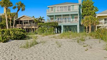 A beachfront property with a two-story building featuring balconies and a covered porch.