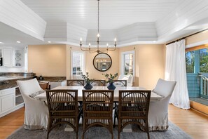 A spacious dining area with a large table, multiple chairs, and a chandelier. - Walks on the Shores Private Beach Front Access (Indian Shores)