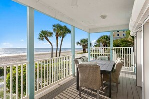 A covered outdoor area with a view of the beach, a table with chairs, and a railing. - Walks on the Shores Private Beach Front Access (Indian Shores)