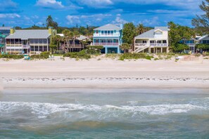 A beachfront property with multiple buildings, including a blue house with a balcony, a white house with a porch, and a yellow building with a covered area. - Walks on the Shores Private Beach Front Access (Indian Shores)