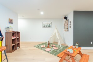 Ein Zimmer mit einer Holzhülle, einem grünen Teppich, einem Zelt und einer Wanddekoration mit Camping-Alphabet.