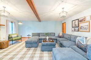 Ein Wohnzimmer mit einem Ecksofa, einem Couchtisch, einer Lampe und gerahmten Bildern an der Wand.