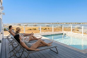Un espace aménagé au bord de la piscine, avec des chaises longues et une vue sur un plan d’eau.