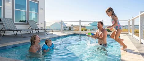 Una piscina con sillones de descanso y vistas al mar.