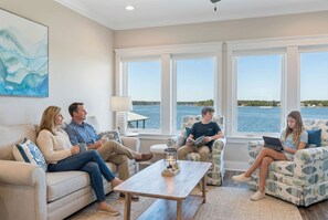 A living room with a view of the water, a coffee table, and a painting on the wall. - Waterfront Views - Walk to Beach - Heated Pool (Gulf Shores)