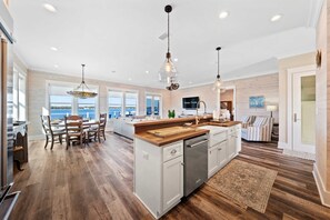 A spacious kitchen with a large island, wooden flooring, and a view of the sea through large windows. - Waterfront Views - Walk to Beach - Heated Pool (Gulf Shores)