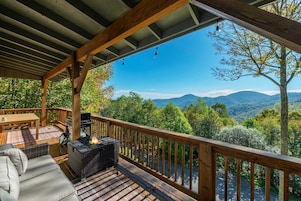 Um deck coberto ao ar livre, com churrasqueira e área de estar, com vista para uma paisagem montanhosa.
