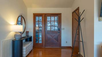 A hallway with a wooden floor, a door with glass panels, a coat rack, and a radiator.