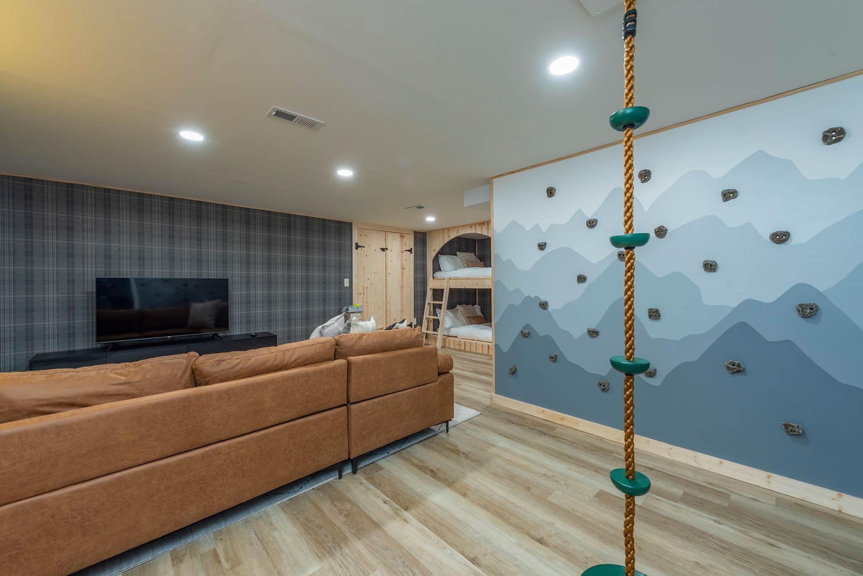 A modern living room with a sofa, television, and a climbing wall.