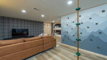 A modern living room with a sofa, television, and a climbing wall.