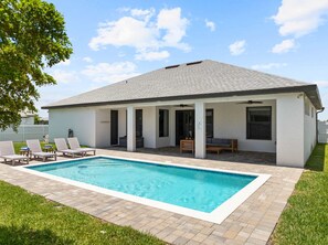 Een modern huis met zwembad, overdekt terras en een buiten zitgedeelte.