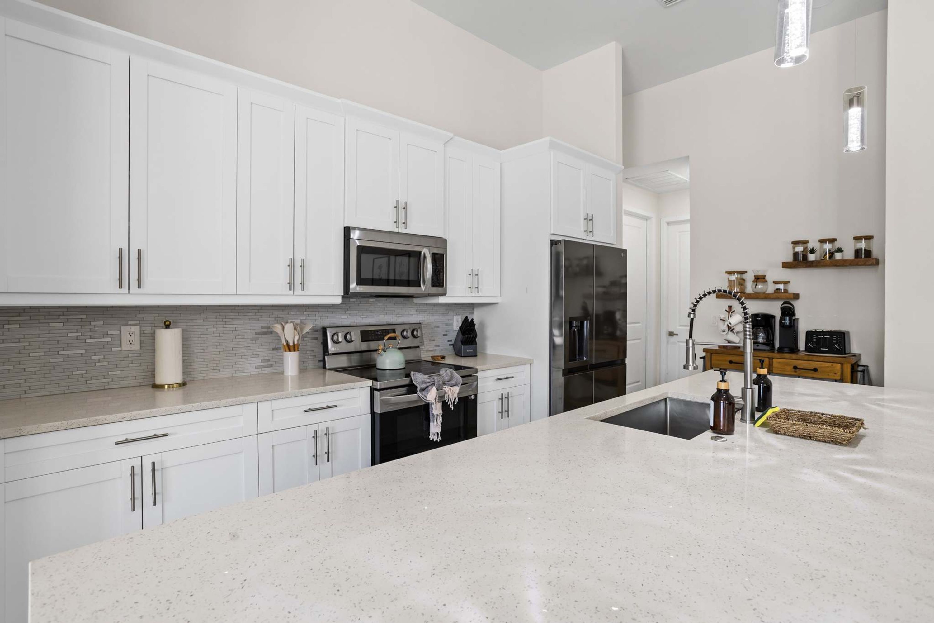 A modern kitchen with white cabinetry, stainless steel appliances, and a granite countertop.
