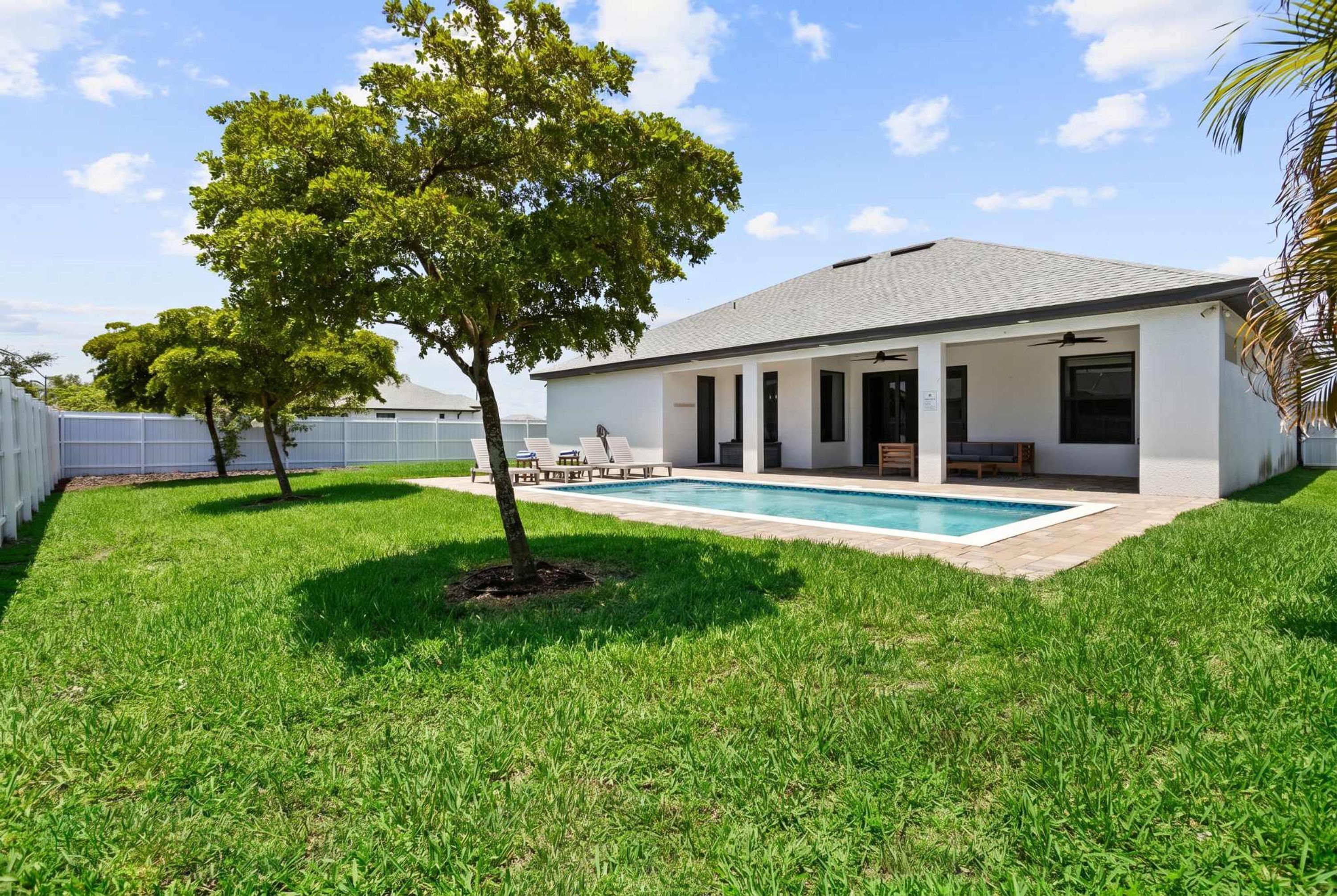 A modern house with a swimming pool, a covered patio, and a well-maintained lawn.