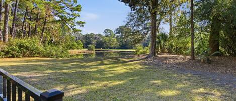 A park with a pond, trees, and a wooden fence.