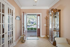 A hallway with a wooden cabinet, a chair, and a door leading outside. - Vacation Paradise - Private Pool Fire Pit BBQ (Hilton Head Island)