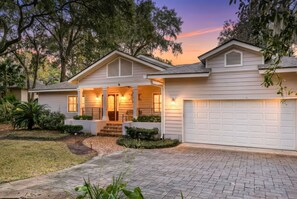 A two-story house with a covered front porch, a garage, and a brick driveway. - Vacation Paradise - Private Pool Fire Pit BBQ (Hilton Head Island)