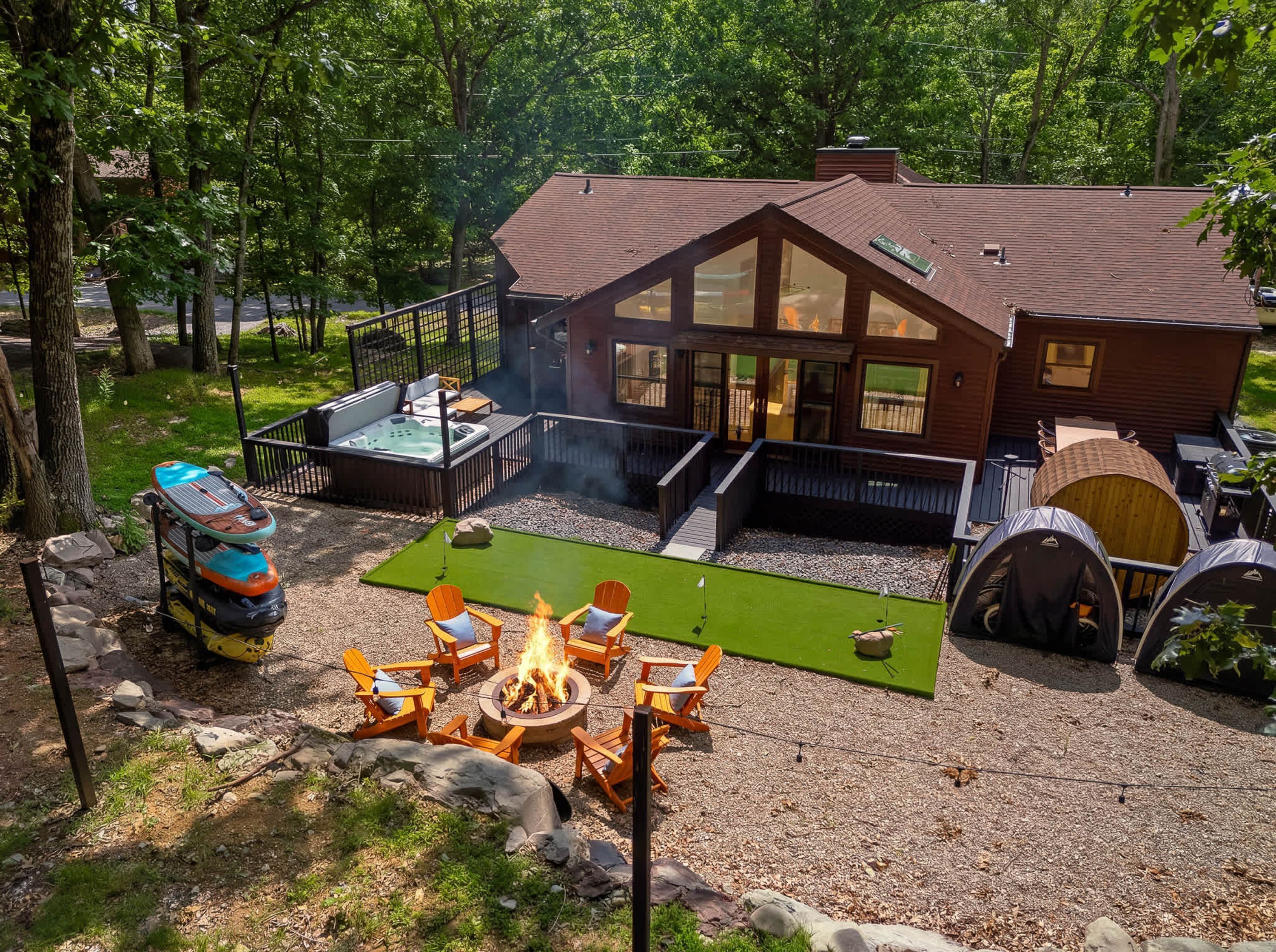 A cabin with a hot tub, outdoor seating, and a fire pit.