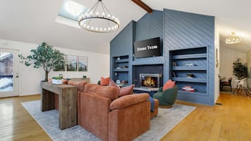 A modern living room with a sectional sofa, a fireplace, and a mounted TV.