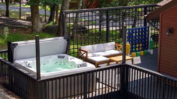 A hot tub area with a wooden deck, a white sofa, and a wooden table.