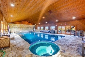 An indoor swimming pool with stone flooring, wooden ceiling, and seating areas. - Lake Mathews Estate Indoor Pool Pickleball Beach Volleyball (Perris)