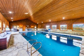An indoor swimming pool with stone flooring, wooden ceiling, and a seating area with cushions. - Lake Mathews Estate Indoor Pool Pickleball Beach Volleyball (Perris)