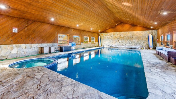 An indoor swimming pool with a wooden ceiling and stone walls. - Lake Mathews Estate Indoor Pool Pickleball Beach Volleyball (Perris)