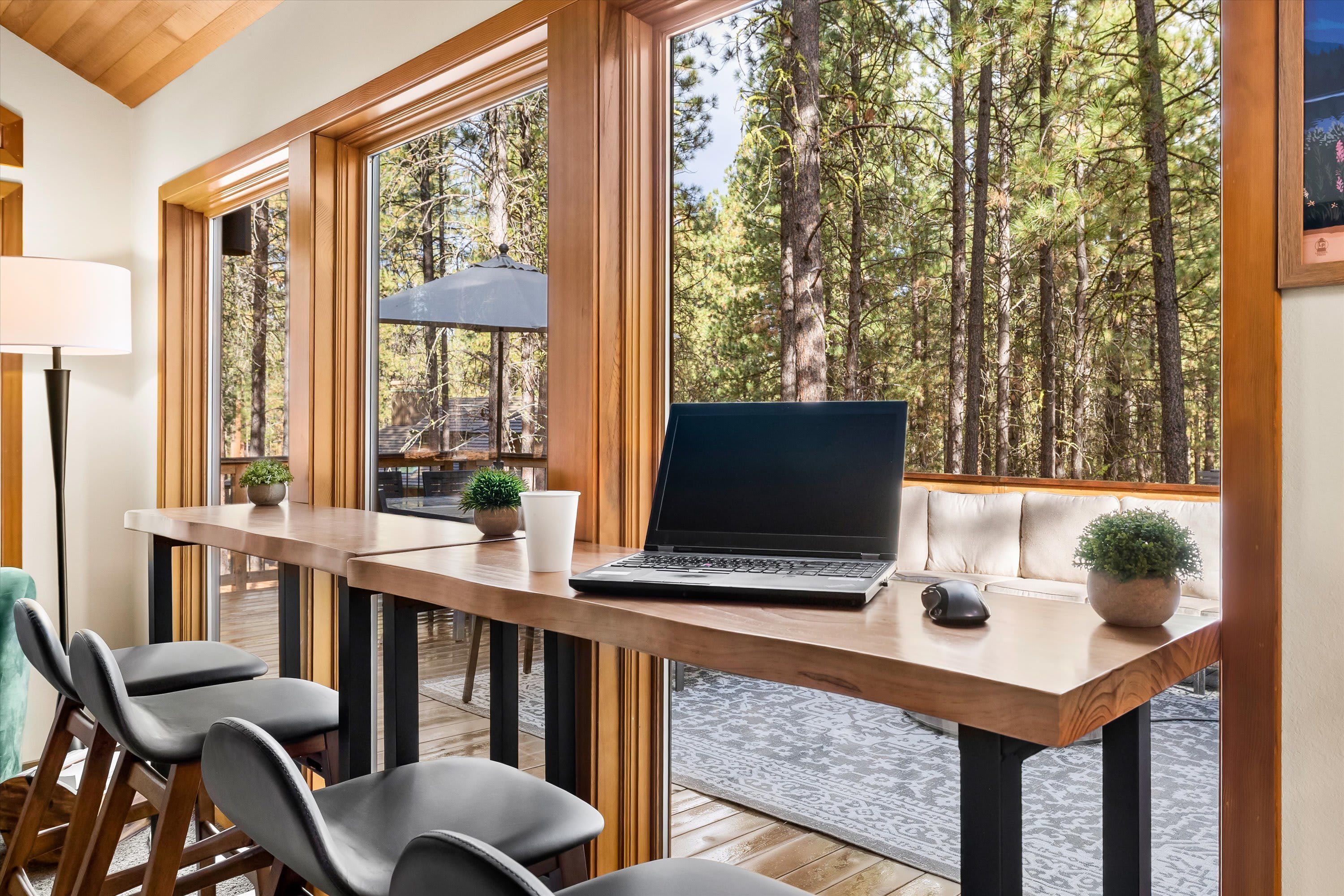 Un bureau en bois avec un ordinateur portable, deux plantes en pot et une tasse blanche.