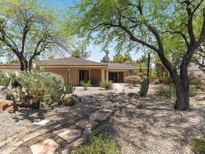 A desert-style house with a paved driveway, surrounded by cacti and trees. - Waz-4901 E Sunnyside Dr (Scottsdale)