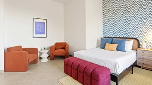 Ein modernes Schlafzimmer mit einem Bett, zwei Sesseln, einem kleinen Beistelltisch und einer Wand mit Muster.
