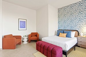 Ein modernes Schlafzimmer mit einem Bett, zwei Sesseln, einem kleinen Beistelltisch und einer Wand mit Muster.