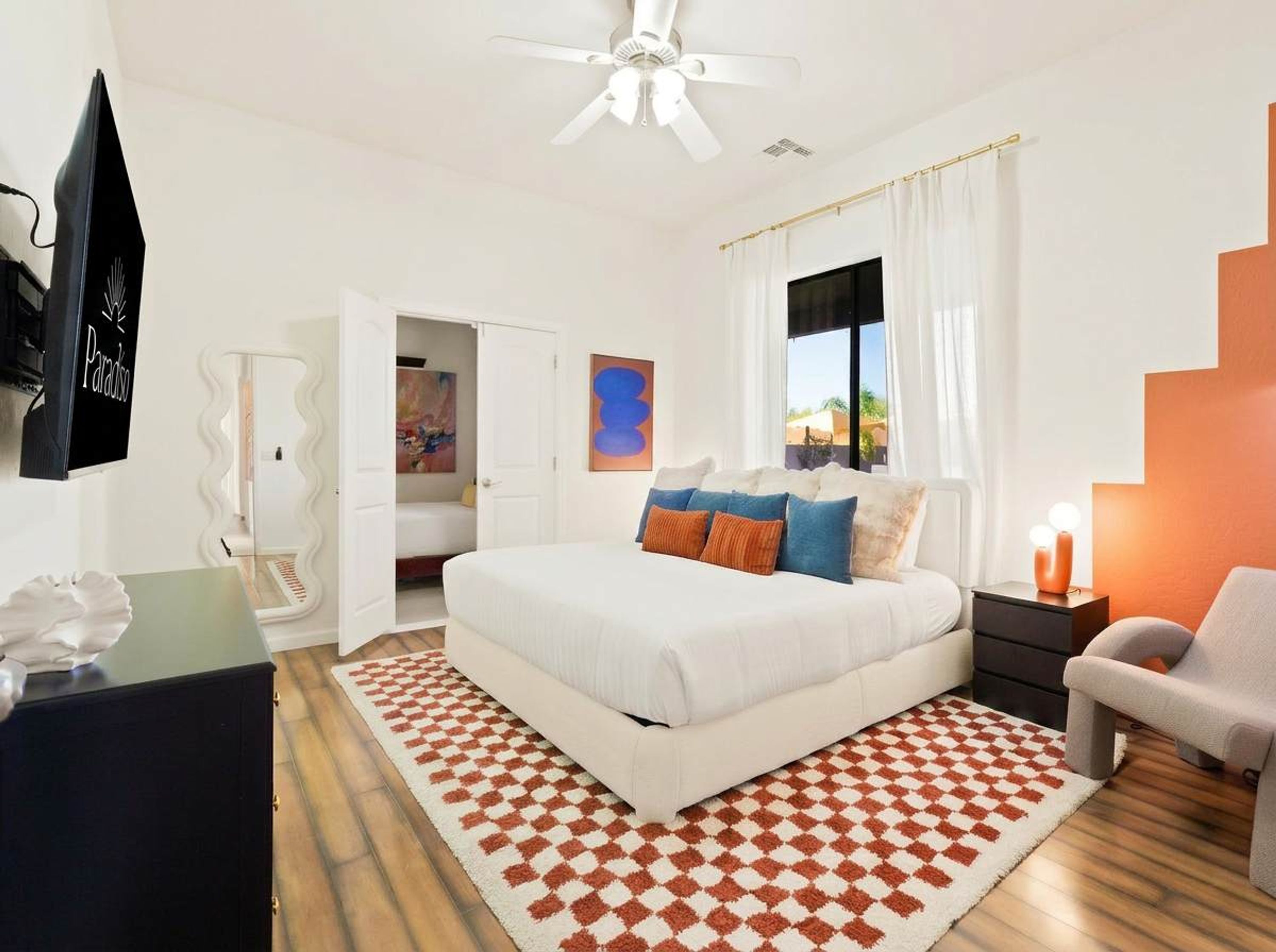 A bedroom with a bed, a nightstand, a chair, a ceiling fan, and a window with curtains.